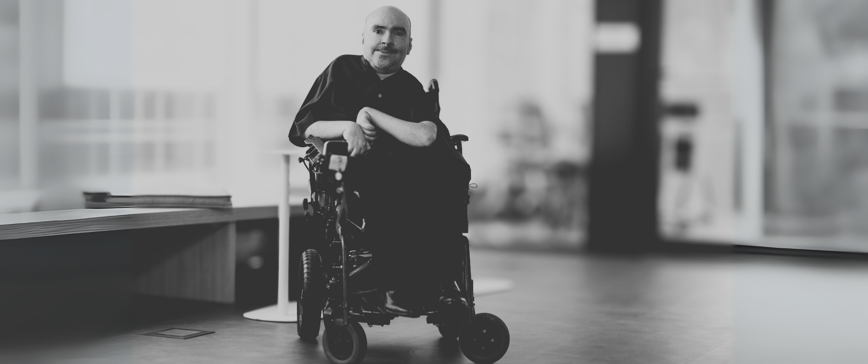 Um homem de cadeira de rodas motorizada em um escritório.